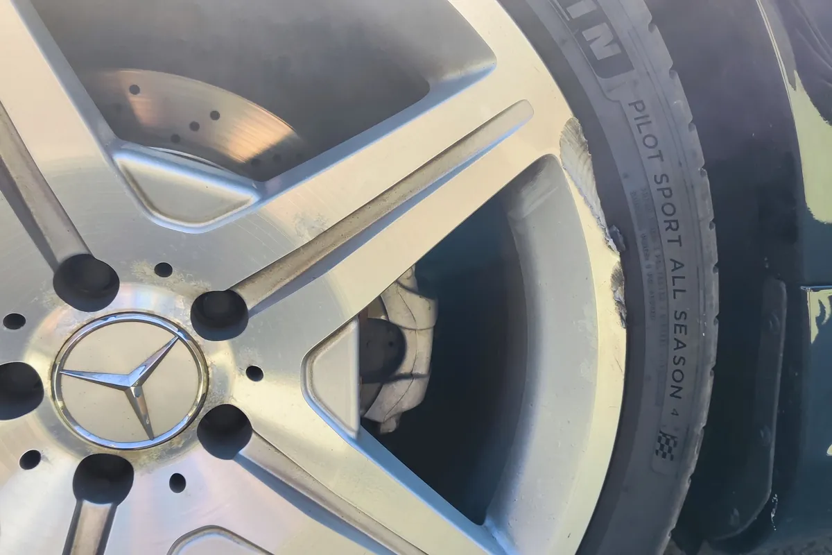 Otarta krawędź aluminiowej felgi z oponą — uszkodzenie rantu widoczne przy stopce